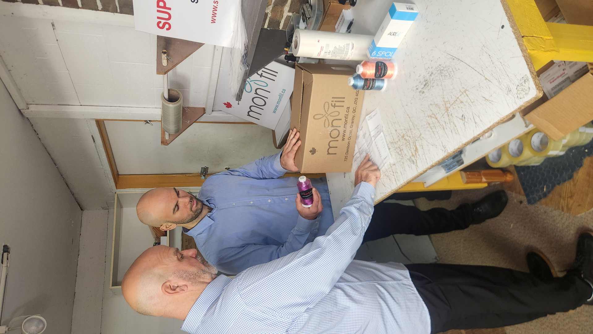 Johnny and Tommie Larochelle reviewing an order beside a Monfil box